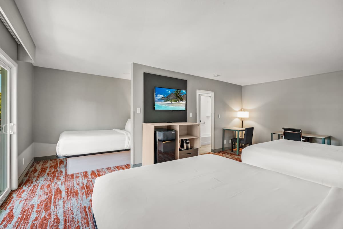 A hotel room with two beds, a television, a desk, and a chair.
