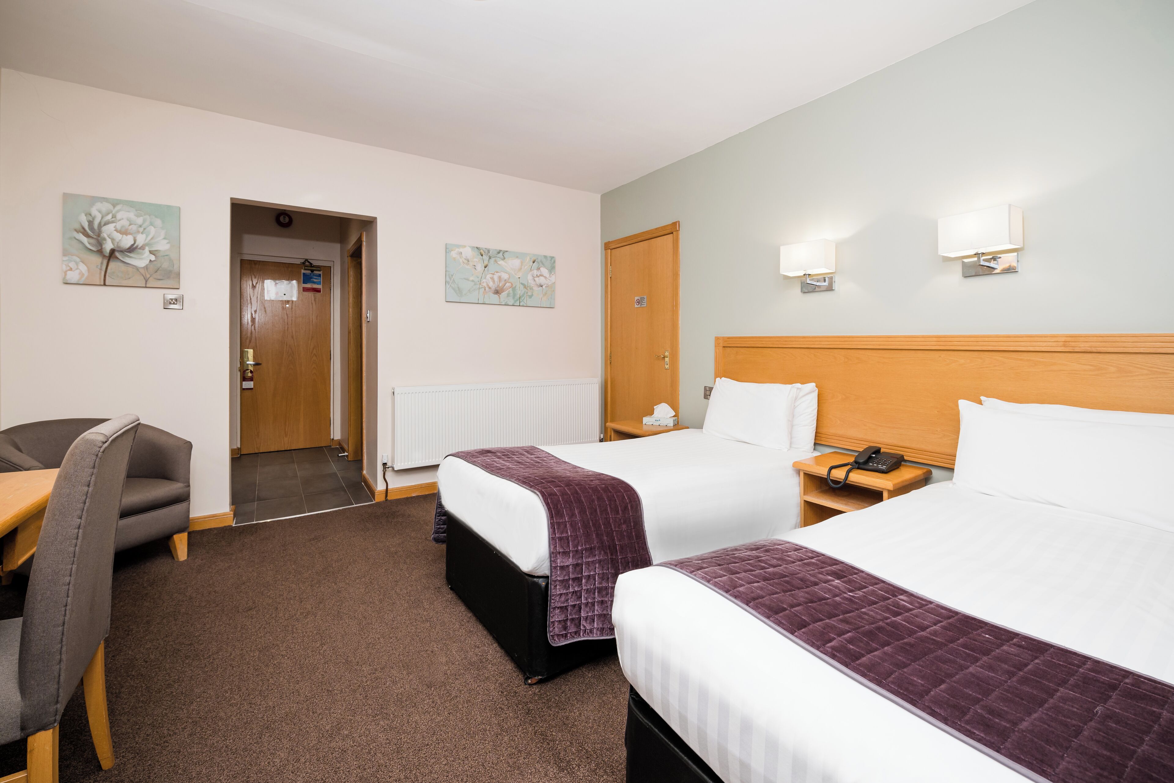 Een hotelkamer met twee bedden, een bureau en een stoel.