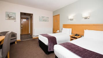 Een hotelkamer met twee bedden, een bureau en een stoel.