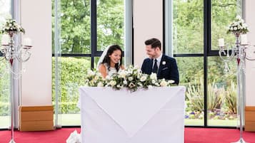 A wedding ceremony with a white altar table, floral arrangements, and candle holders.