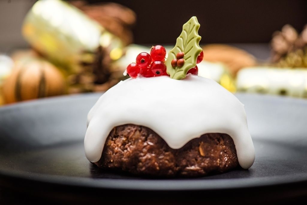 Un postre con glaseado blanco y bayas rojas sobre un plato.
