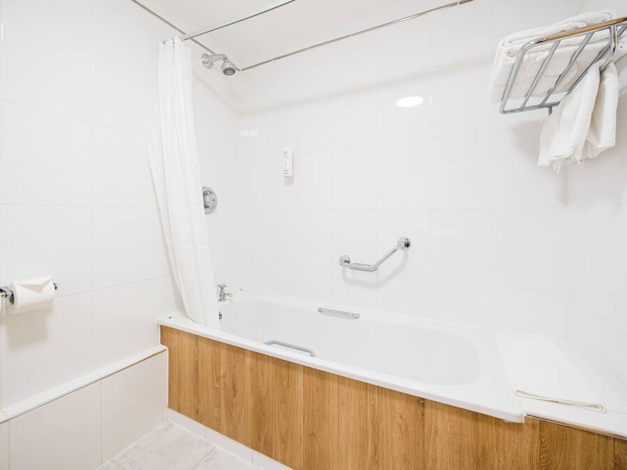 Un baño moderno con tocador de madera, bañera y zona de ducha.