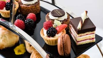 A variety of desserts including tarts, macarons, and layered cakes, arranged on a tray.