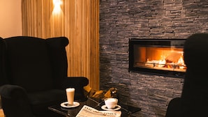 A cozy seating area with a fireplace, a table with a newspaper, and a cup of coffee. - La Mon Hotel And Country Club (Newtownards)