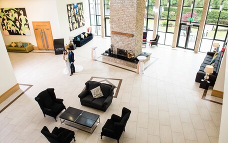 A spacious lobby with a stone fireplace, comfortable seating, and large windows offering views of the outdoors.