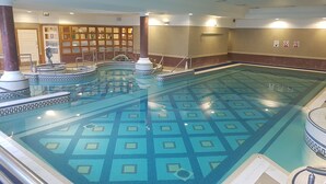 A large indoor swimming pool with a geometric tile pattern, surrounded by a tiled deck and a wall with framed pictures. - La Mon Hotel And Country Club (Newtownards)