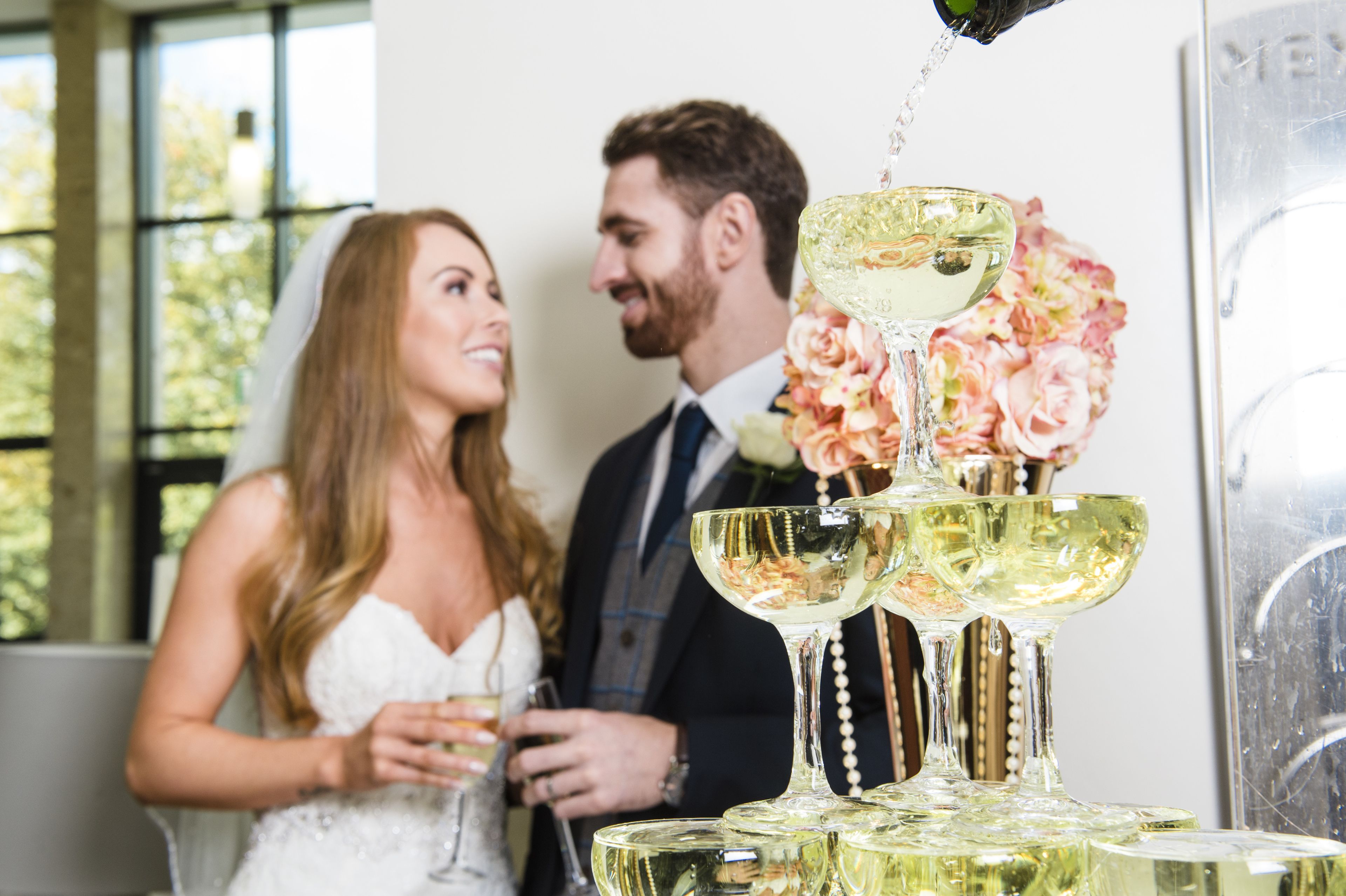 A wedding reception with a tiered champagne fountain and floral decorations.