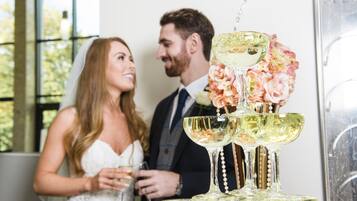 A wedding reception with a tiered champagne fountain and floral decorations.