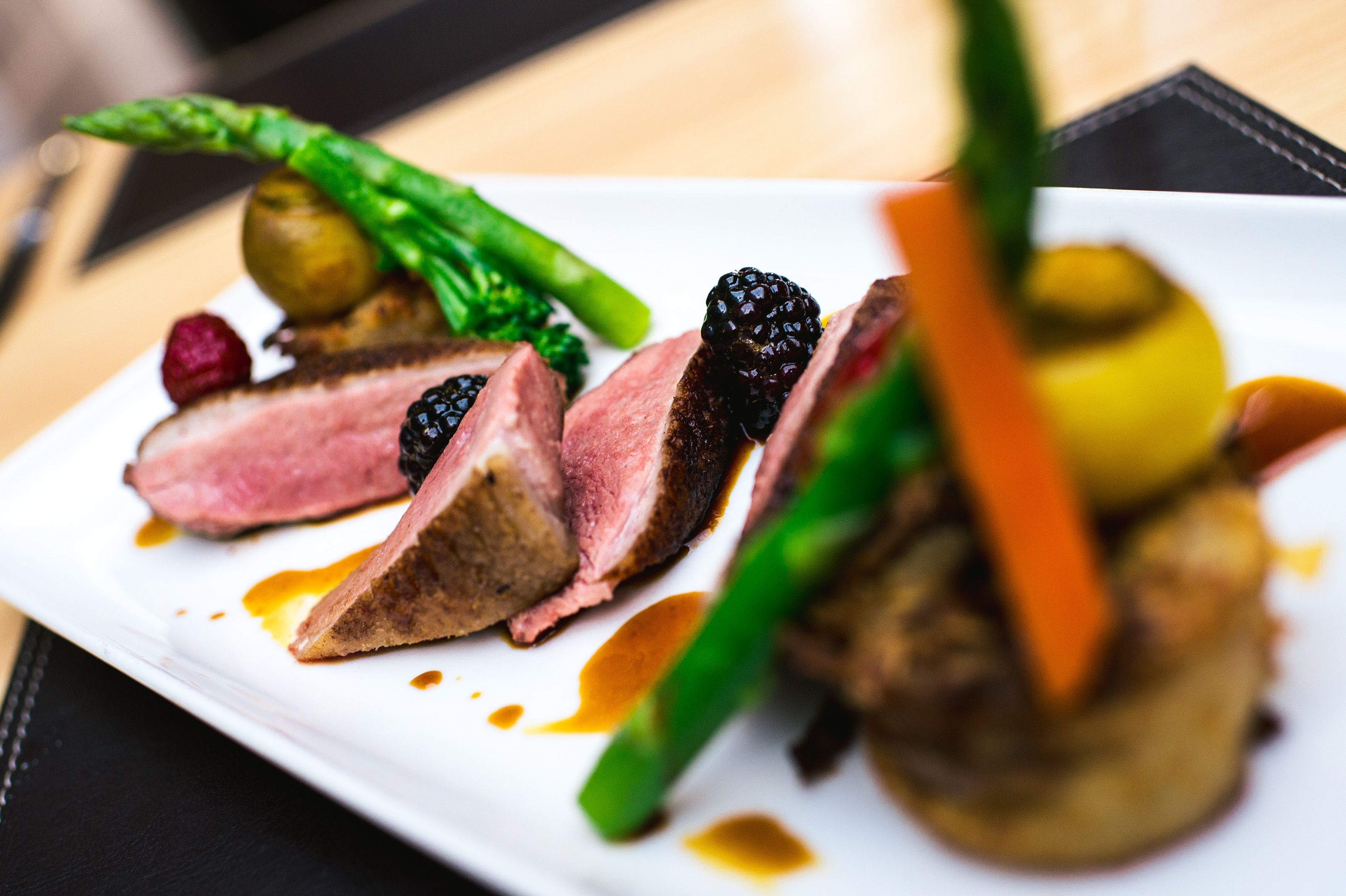 A plate of food with sliced meat, vegetables, and berries.