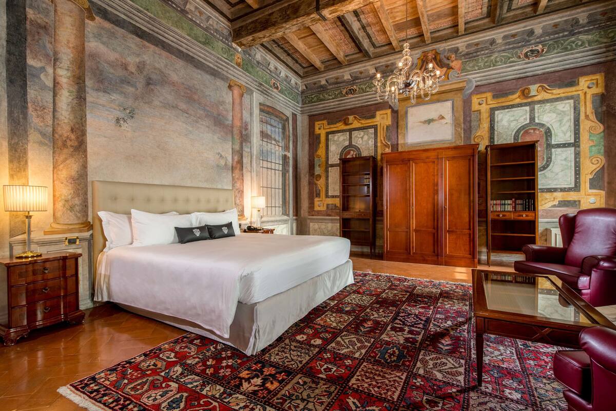 Ein geräumiges Schlafzimmer mit einem großen Bett, einem Holzschrank, einem Glastisch und einem roten Ledersessel.