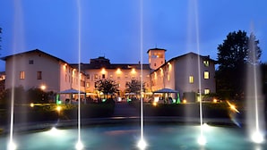 Een hotel met een centrale binnenplaats, meerdere fonteinen en een toren.