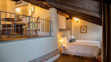 A bedroom with a bed, a nightstand, a lamp, a chair, and a view of the balcony.