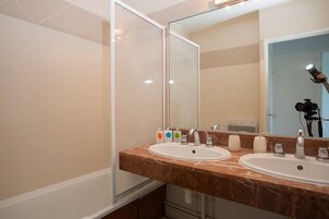 Ein Badezimmer mit zwei Waschbecken, einem großen Spiegel und einer Duschkabine.