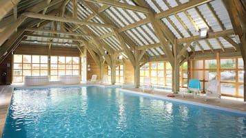 Una piscina techada, sillones reclinables de piscina