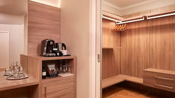 Een moderne badkamer met houten kastjes, een wastafel met koffiezetapparaat en een hangende douchegordijn.