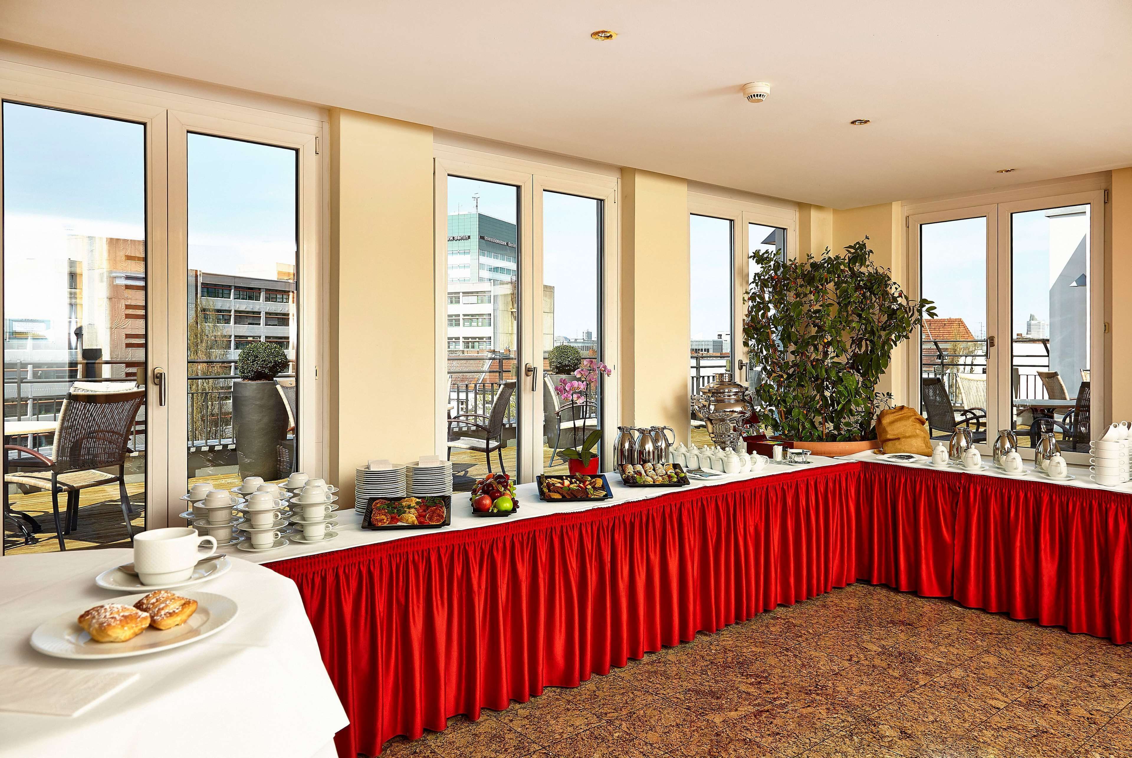 A conference room with a long table, red tablecloth, and various breakfast items.
