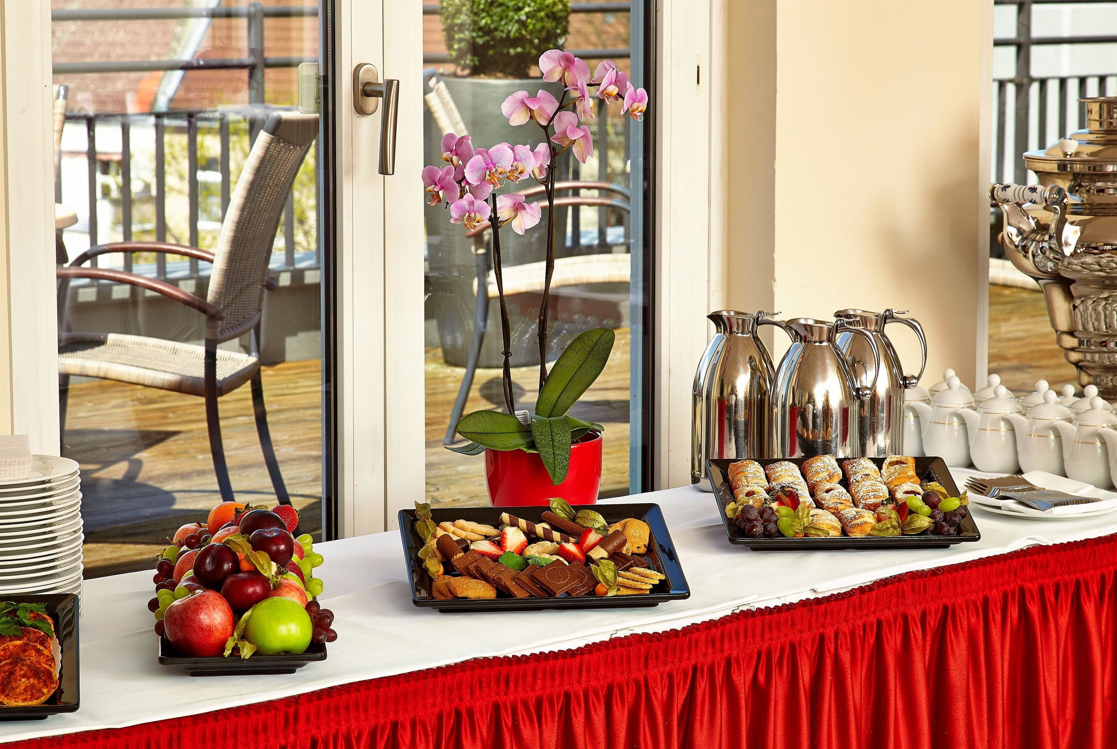 A buffet table with various food items, a red chair, and a potted plant.