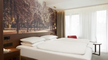 Hotellihuone, jossa on suuri sänky, pieni pöytä, tuoli ja seinälle asennettu televisio.