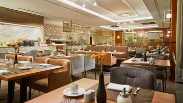 Ein modernes Restaurant mit verschiedenen Essbereichen, darunter eine Bar und Sitzgelegenheiten mit Tischen und Stühlen.