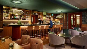 A bar area with a bartender, bar stools, and a variety of bottles and glasses. - HYPERION Hotel Berlin (Berlin)