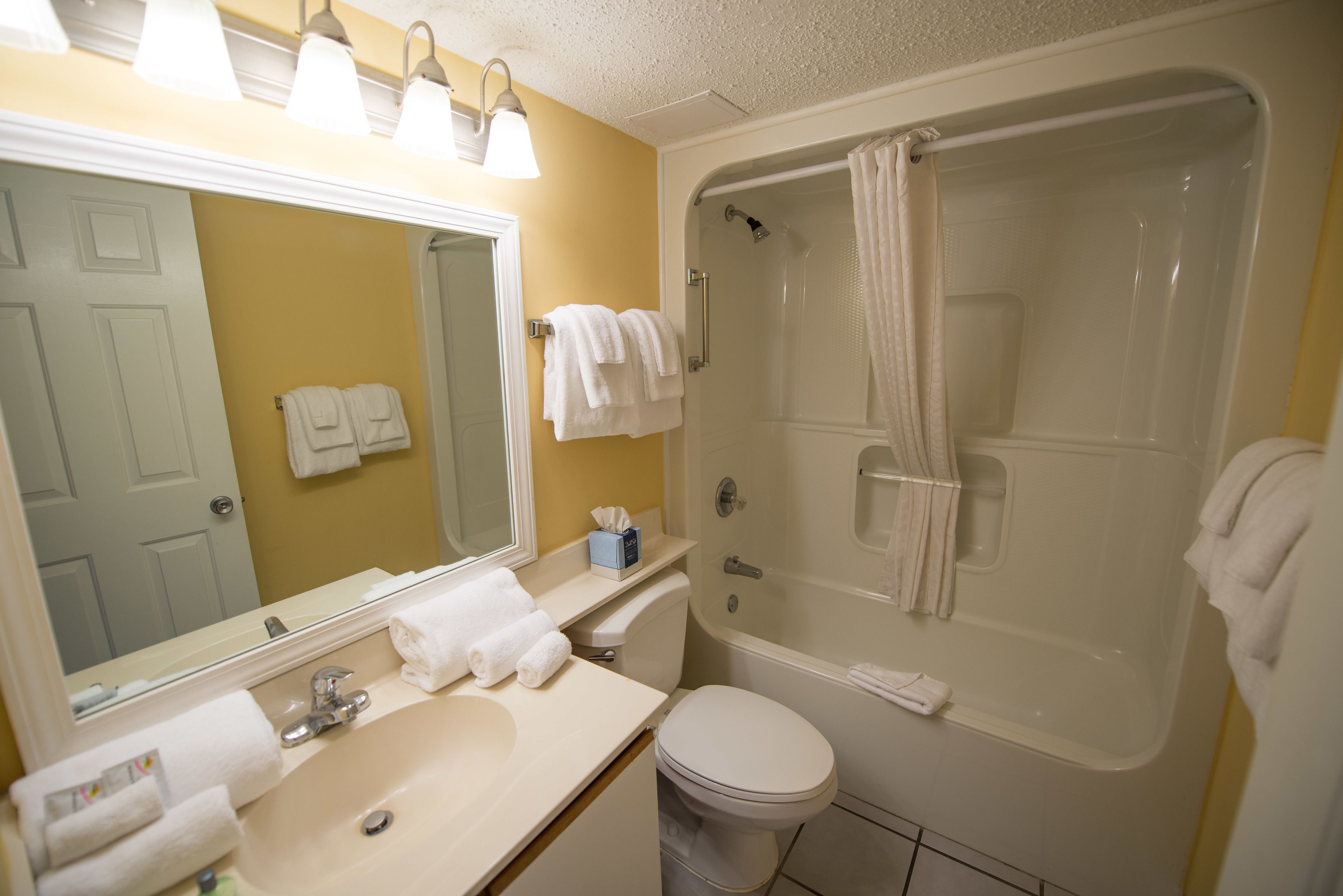 Une salle de bain avec un lavabo, des toilettes et une douche. Il y a des serviettes sur le lavabo et dans la douche.