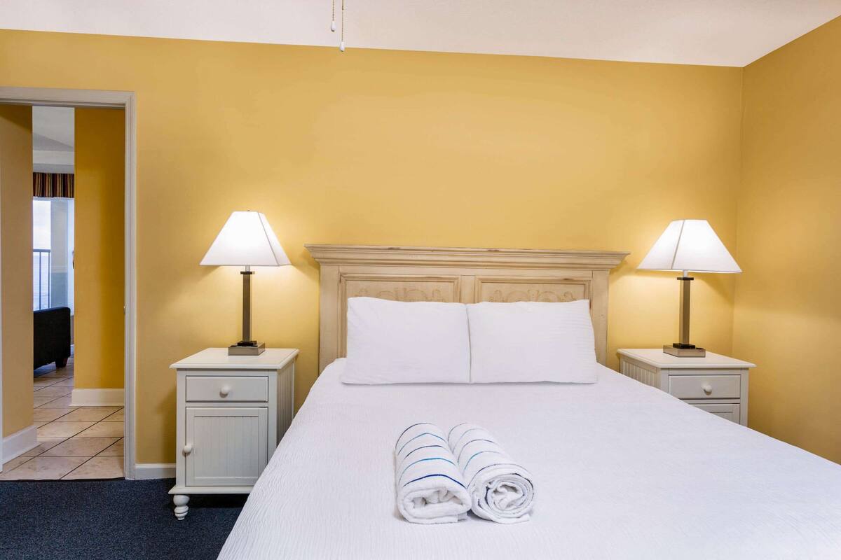 Een hotelkamer met een bed, twee nachtkastjes en twee lampen.
