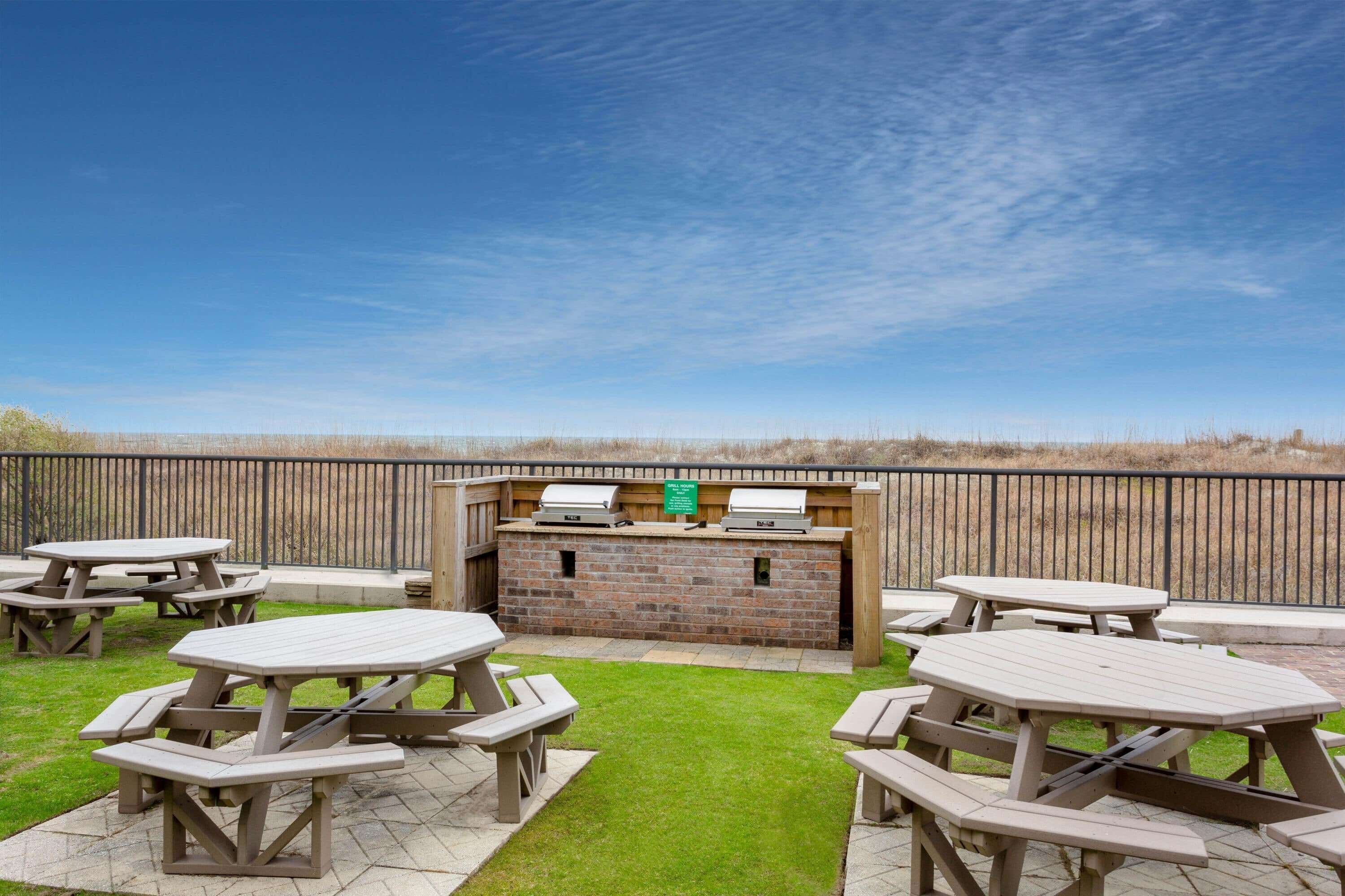 An outdoor patio area with picnic tables and a barbecue grill.