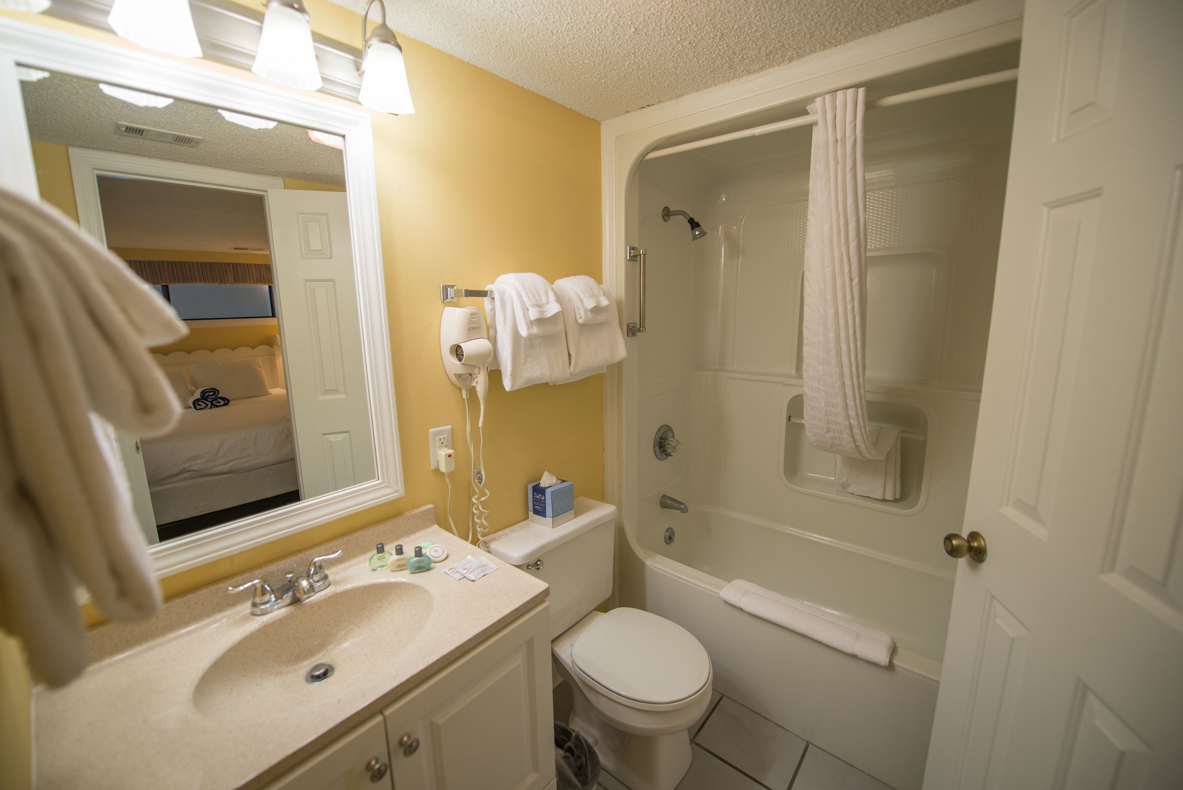 A bathroom with a sink, toilet, and bathtub. There are towels hanging on the wall and a shower curtain.