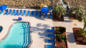 A beach view with a swimming pool, lounge chairs, and a pathway leading to the beach.