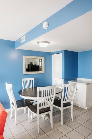 A dining area with a round table and white chairs, a white cabinet, and a blue wall.