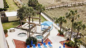 A rooftop pool area with lounge chairs, a hot tub, and a wooden deck.