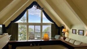 A room with a large window, a bathtub, a chair, a table, and a lamp. - Old Alcohol Plant Hotel (Port Hadlock)