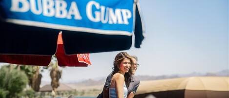 A couple sitting at an outdoor table with a 'Bubba Gump' umbrella in the background.