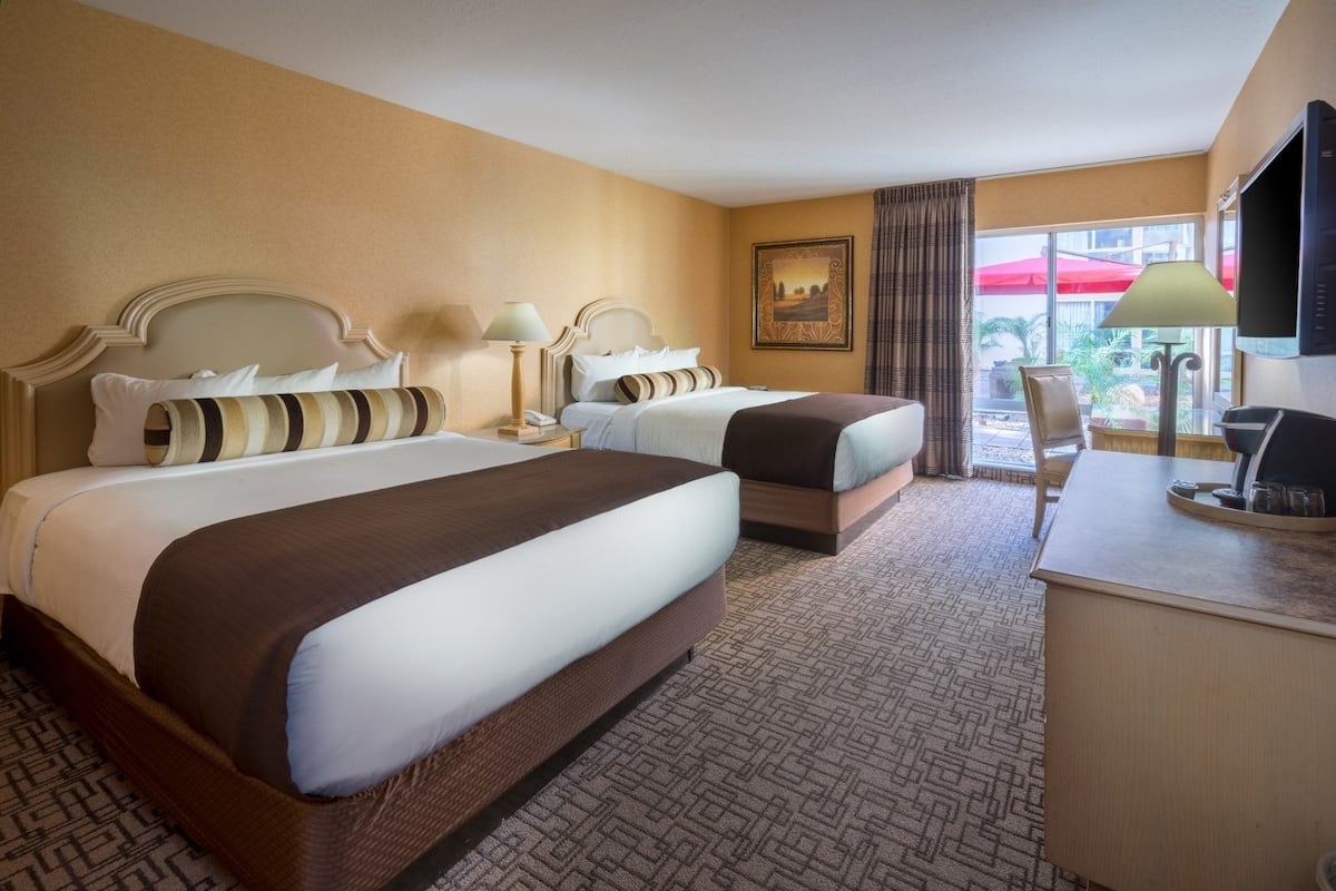 Ein Hotelzimmer mit zwei Betten, einem Schreibtisch und Blick ins Freie.