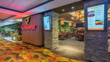 Un hall d’hôtel avec une enseigne « Claim Jumper », un espace restaurant agrémenté de piliers en pierre et un tapis aux couleurs vives.