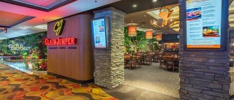 A hotel lobby with a Claim Jumper sign, a restaurant area with stone pillars, and a colorful carpet.