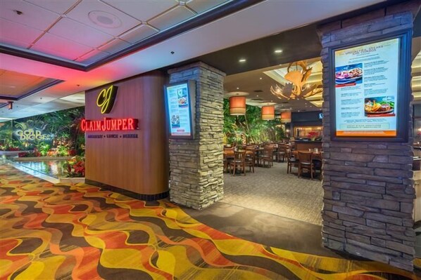 Un hall d’hôtel avec une enseigne « Claim Jumper », un espace restaurant agrémenté de piliers en pierre et un tapis aux couleurs vives.