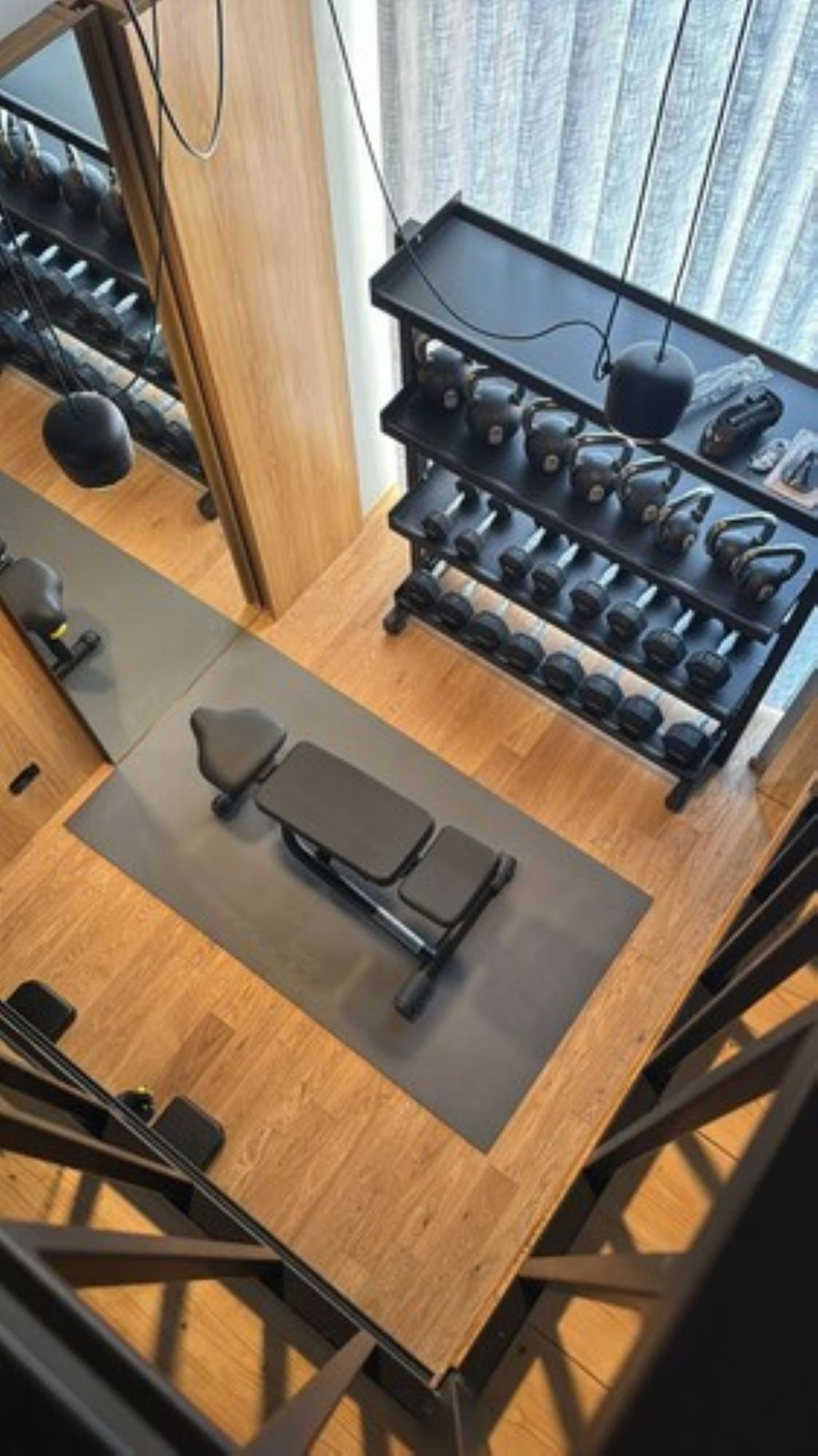 A gym with exercise equipment, a bench, and a rack of dumbbells.
