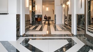 Un moderno vestíbulo de hotel con piso de mármol, un arco central y una zona de estar.