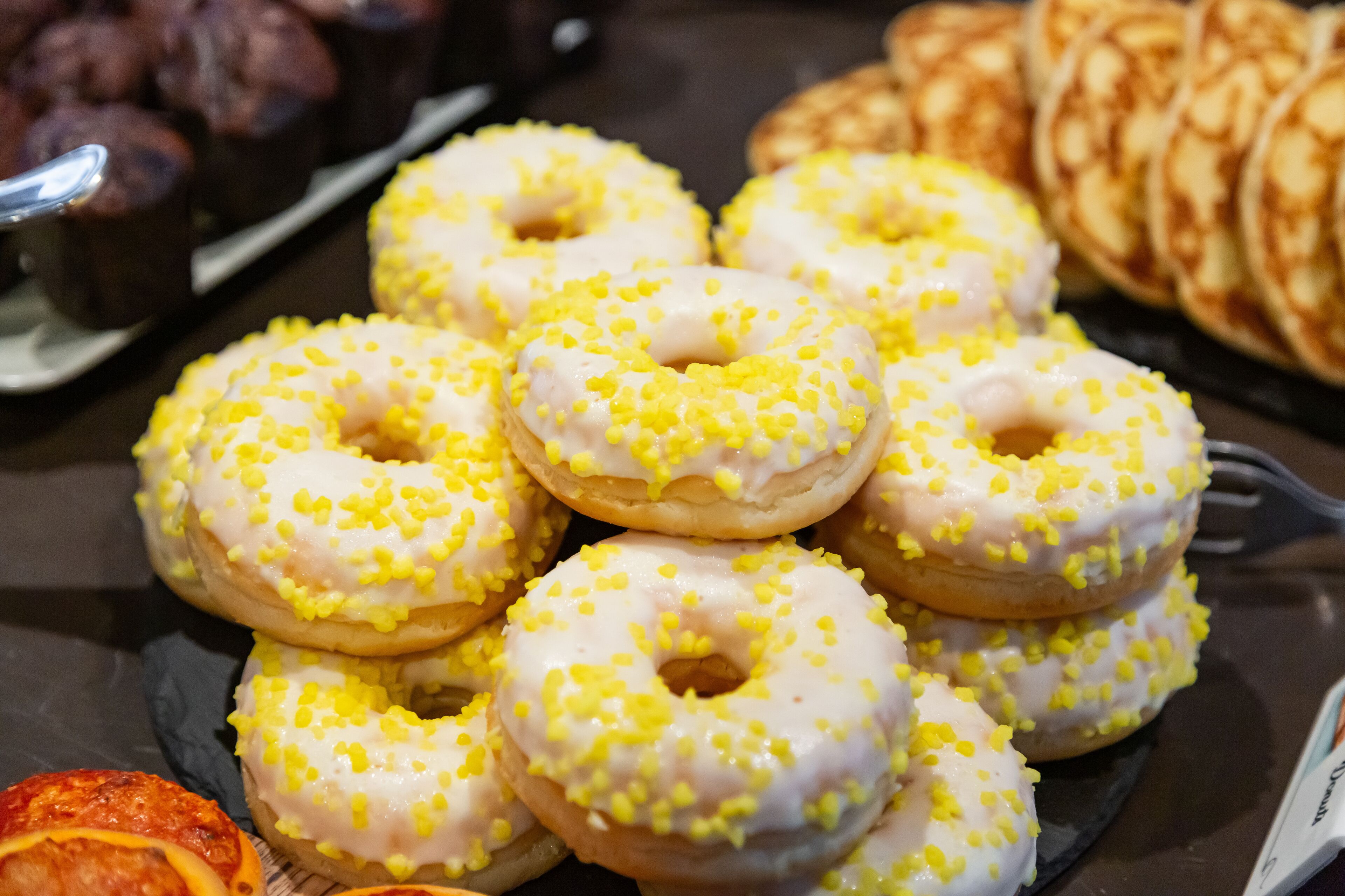 A plate of glazed donuts with yellow sprinkles.