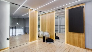 Una habitación moderna con suelo de madera, equipo de ejercicio y un espejo grande.