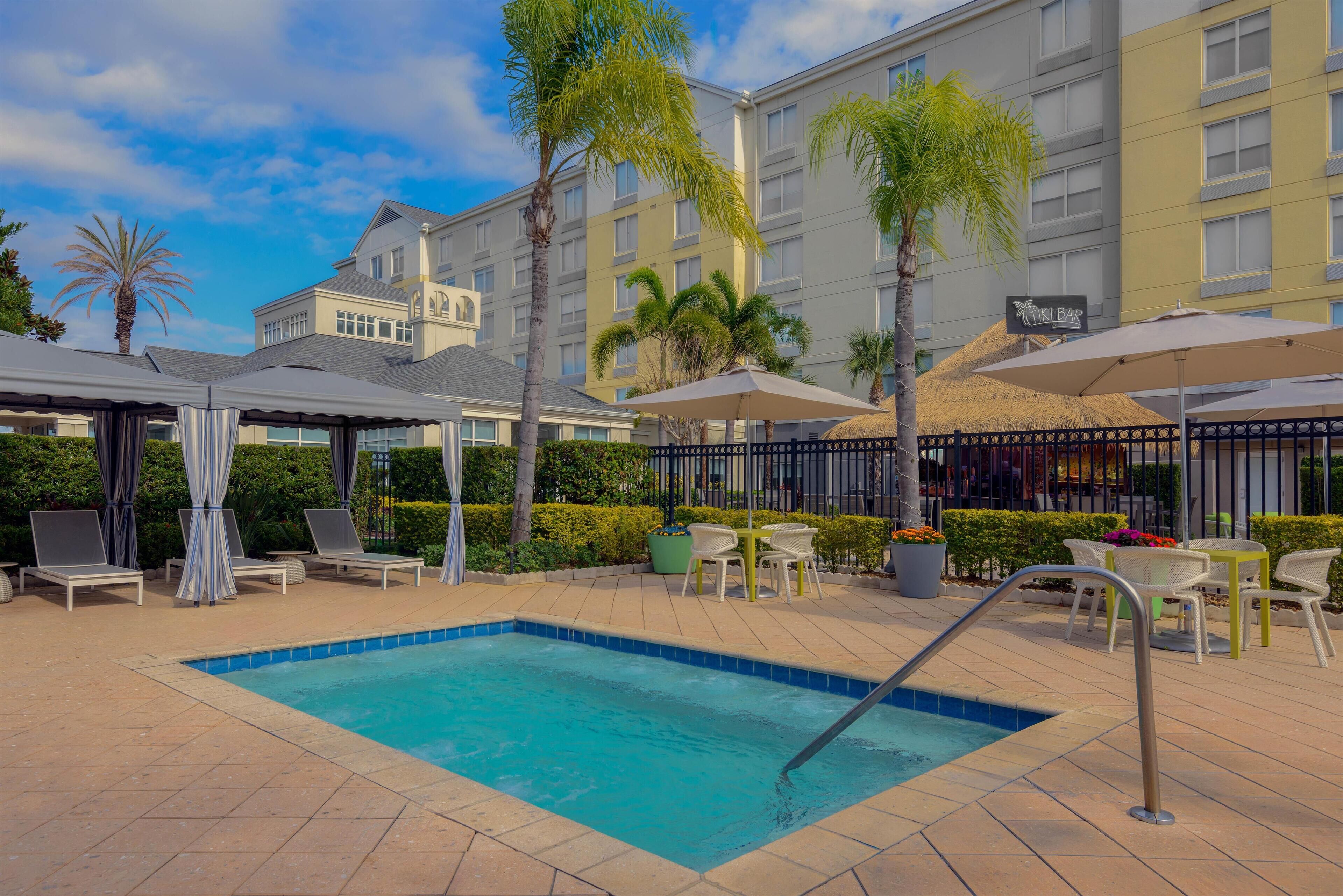 A swimming pool area with lounge chairs, umbrellas, and a bar.
