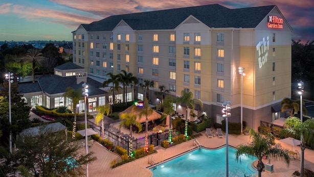 A large hotel with multiple floors, a swimming pool, and outdoor seating areas.