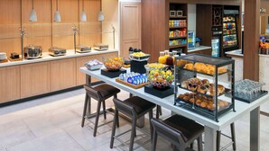 A breakfast buffet with various food items and beverages, a coffee station, and a refrigerated section.
