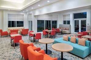 A spacious indoor area with multiple seating arrangements including sofas, chairs, and tables. - Hilton Garden Inn Orlando International Drive North (Orlando)