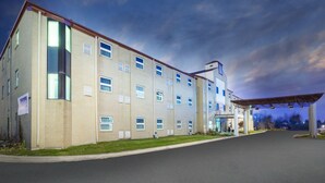 Un edificio de varios pisos con techo plano, ventanas grandes y un área de entrada cubierta.
