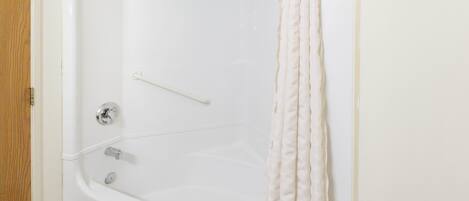 A white bathtub with a shower curtain, a towel rack, and a faucet.