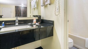 A bathroom with a black countertop sink, a mirror, a coffee maker, and a toilet. - Rodeway Inn Ranger I-20 (Ranger)