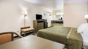 A hotel room with a bed, a desk, a chair, a dresser, a television, and a mirror. - Rodeway Inn Ranger I-20 (Ranger)