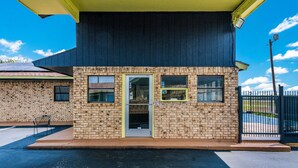 A small brick building with a yellow awning, a door, and windows. - Rodeway Inn Ranger I-20 (Ranger)
